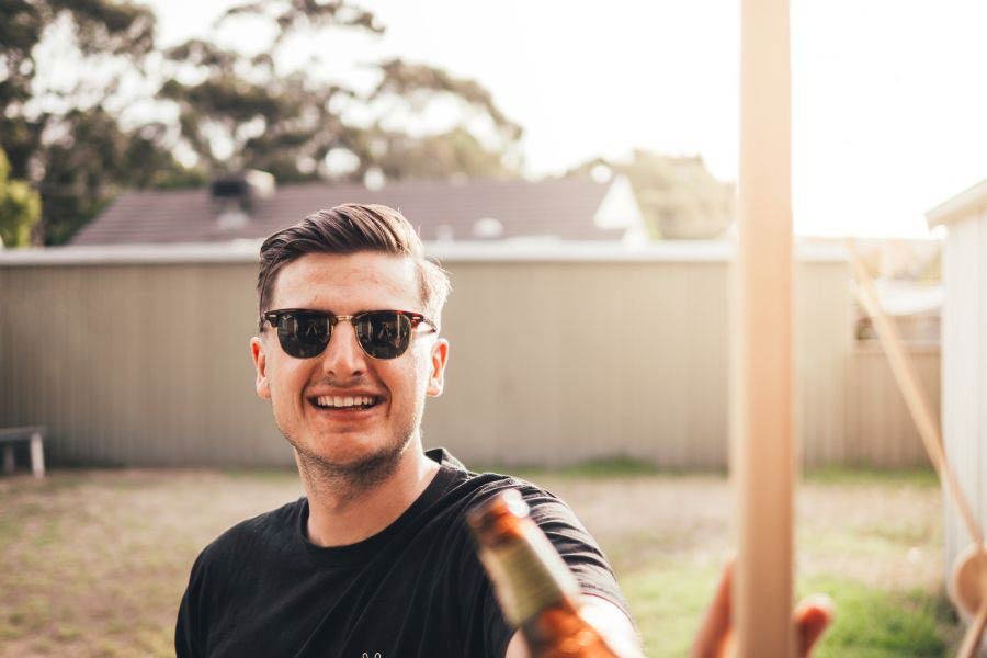 Young man in sunglasses sitting at a picnic table with friends